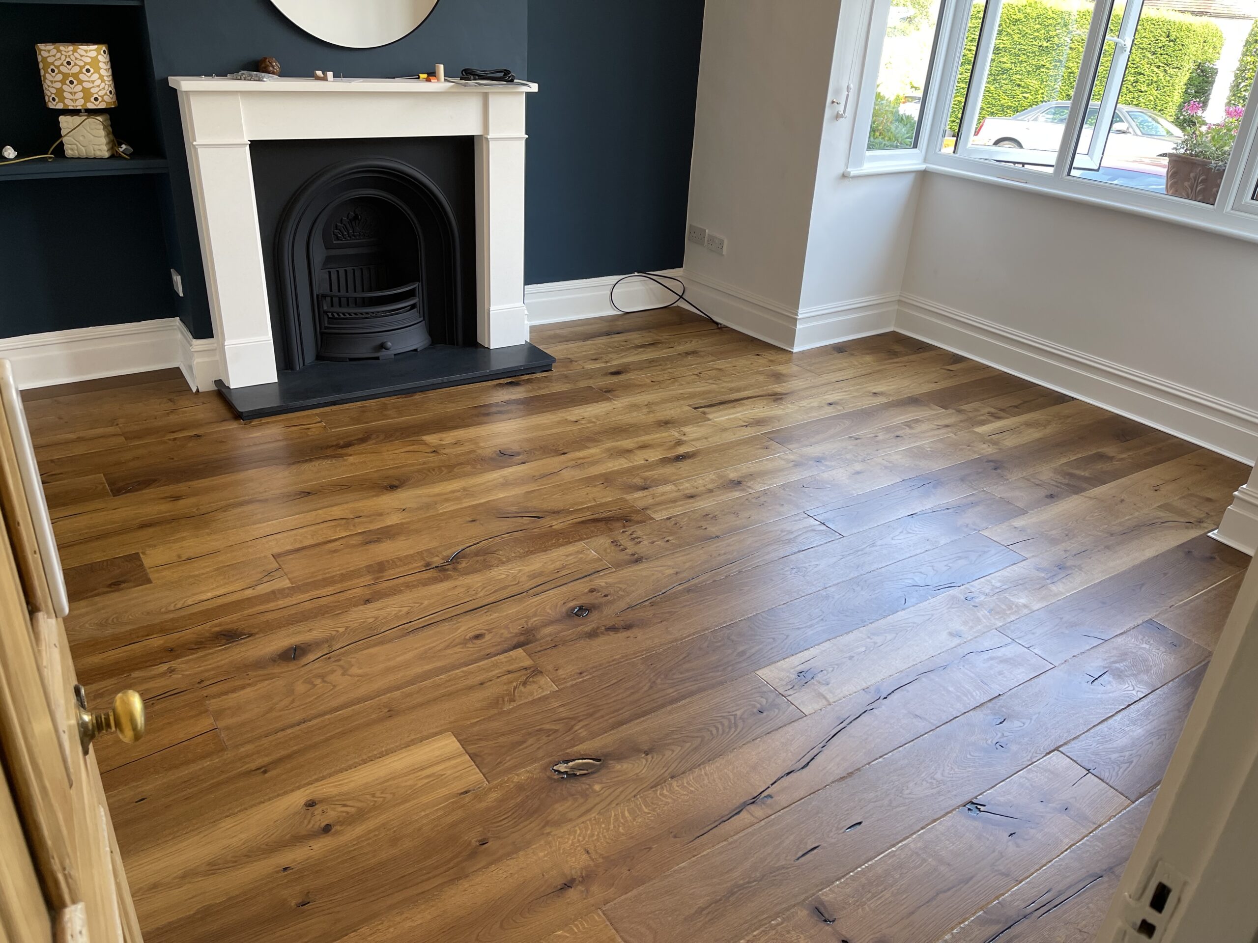 A room with engineered herringbone flooring and a fireplace, showcasing Engineered Herringbone Flooring by Woodford Flooring Ltd in Billericay.