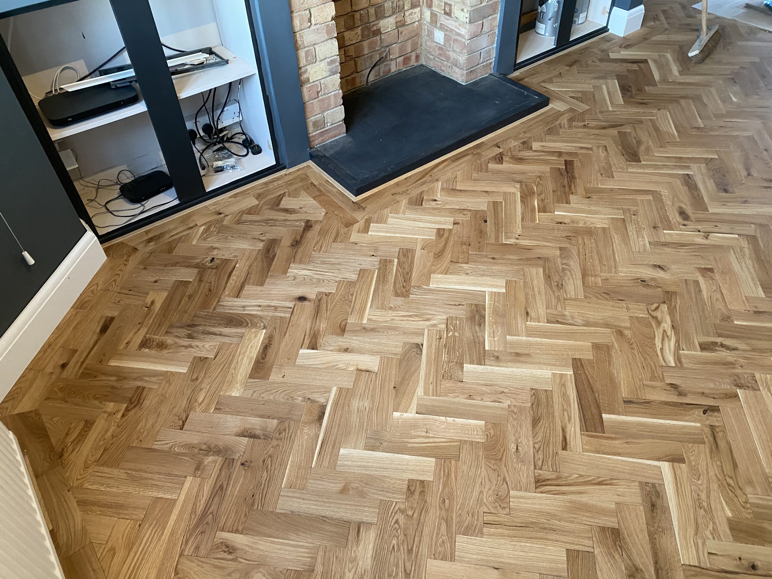 Engineered herringbone flooring in a living room setting, showcasing the intricate wood pattern installed by Woodford Flooring Ltd.