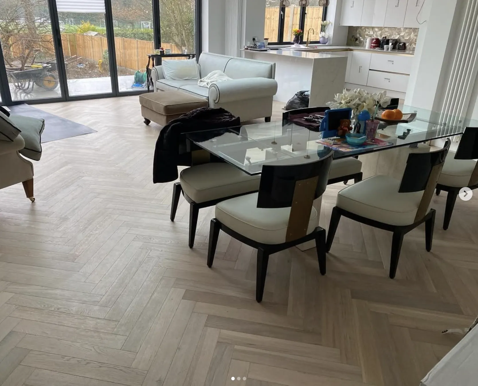 Modern living room with engineered herringbone flooring, glass dining table, and white sofas, showcasing Engineered Herringbone Flooring by Woodford Flooring Ltd.