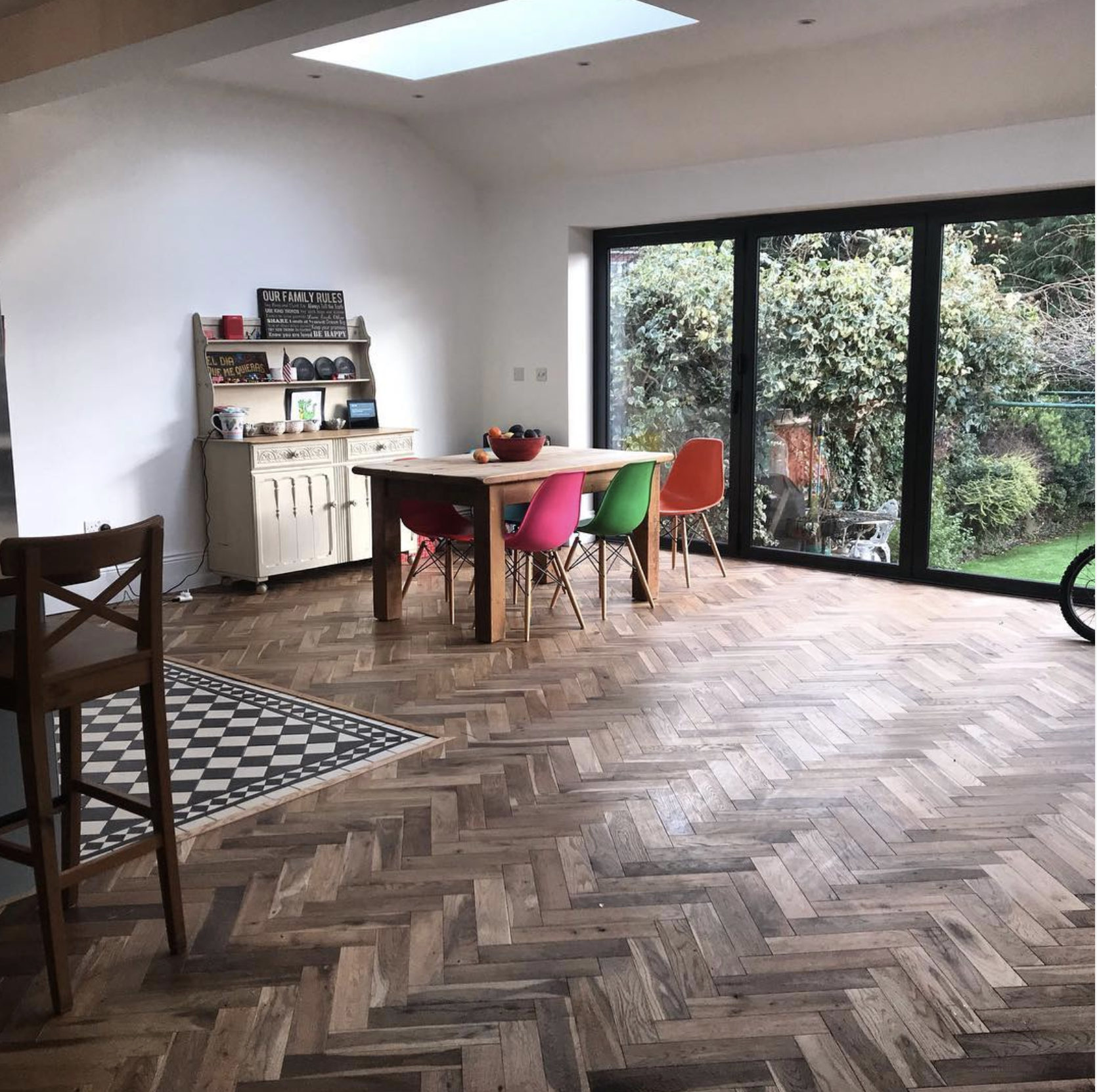 Spacious room with engineered herringbone flooring, colourful chairs, and large windows, showcasing Engineered Herringbone Flooring by Woodford Flooring Ltd.