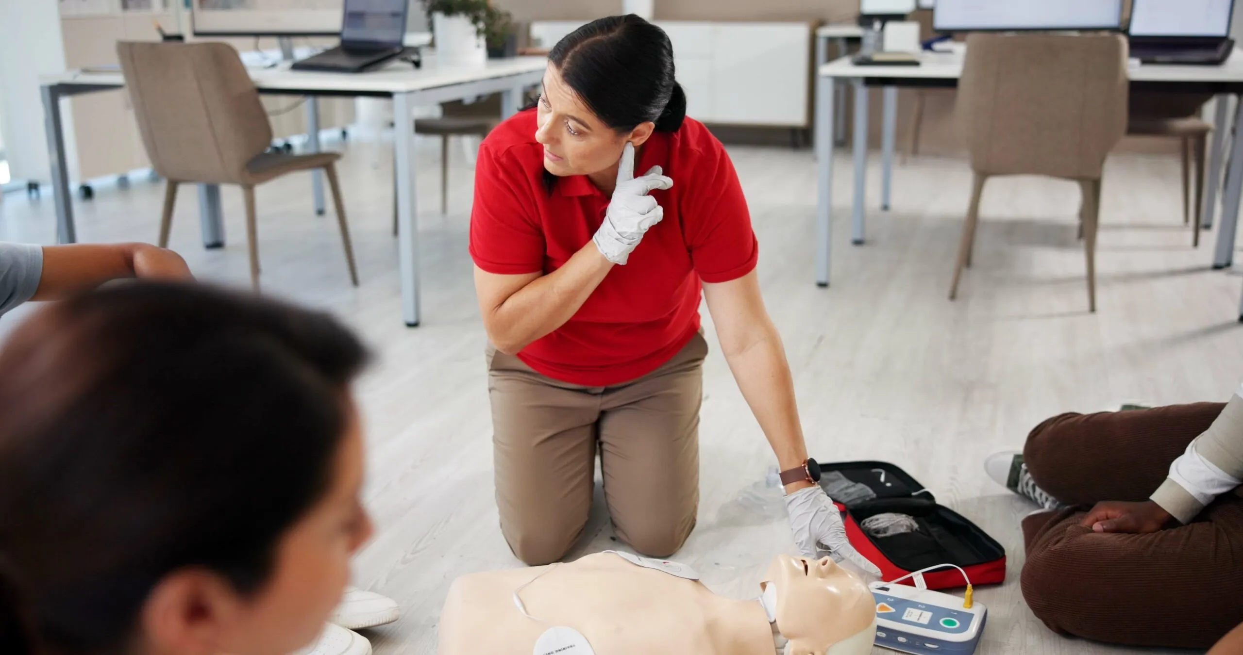 Instructor demonstrating CPR on a mannequin in a classroom setting, part of a First Aid Training Course by AFW Training Ltd in Romford.