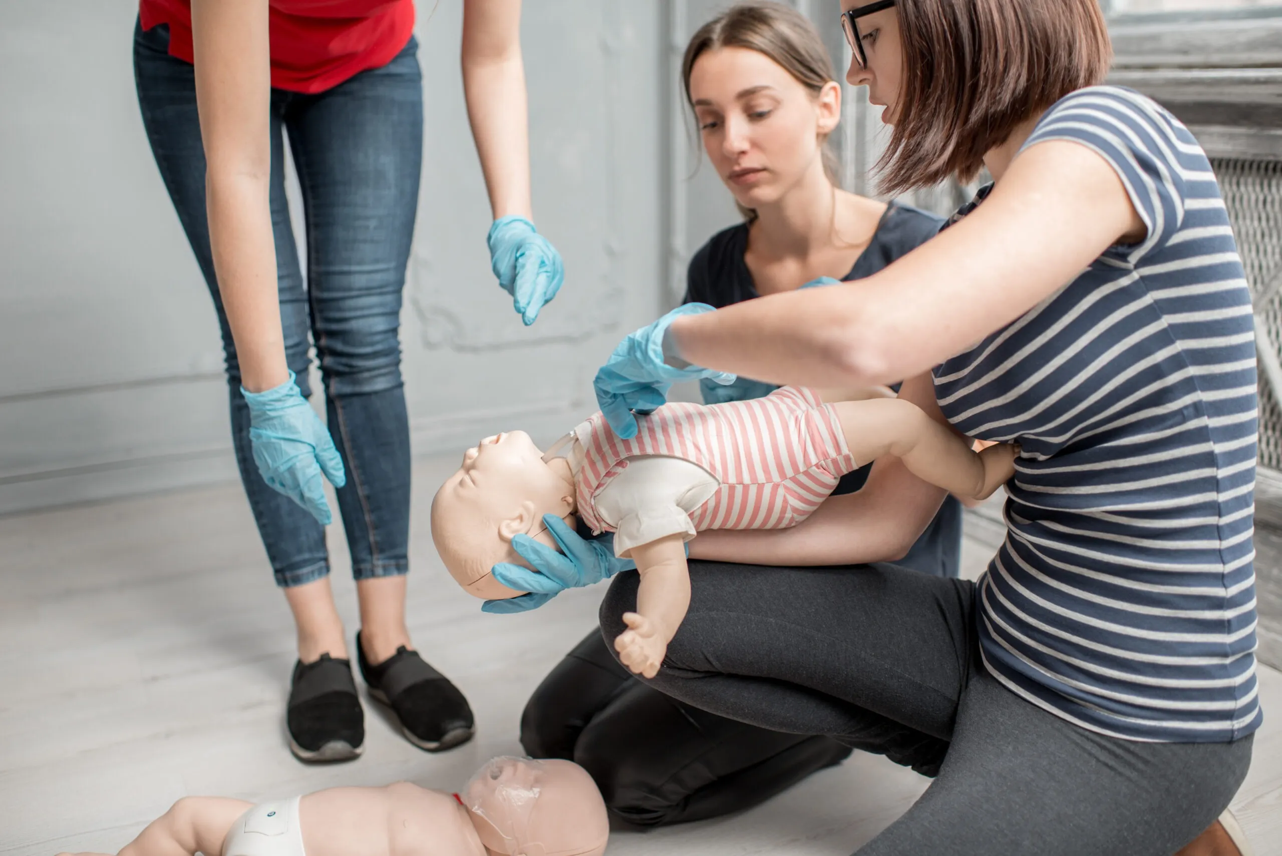 Participants practising infant CPR on a mannequin during a First Aid Training Course by AFW Training Ltd in Purfleet.