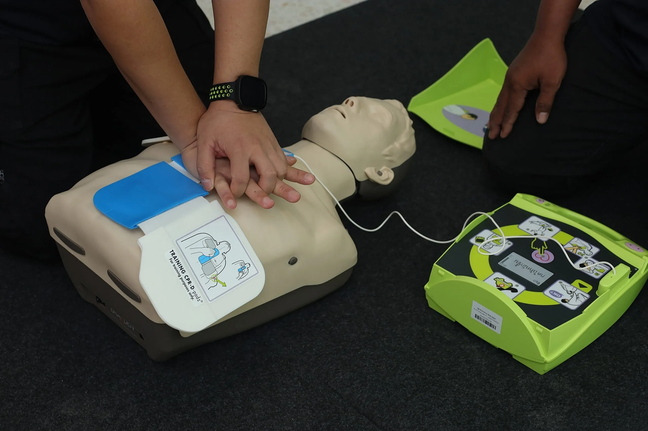 Person performing CPR on a training mannequin with an AED nearby, illustrating AFW Training Ltd's Health &amp; Safety Training Course in West Thurrock.