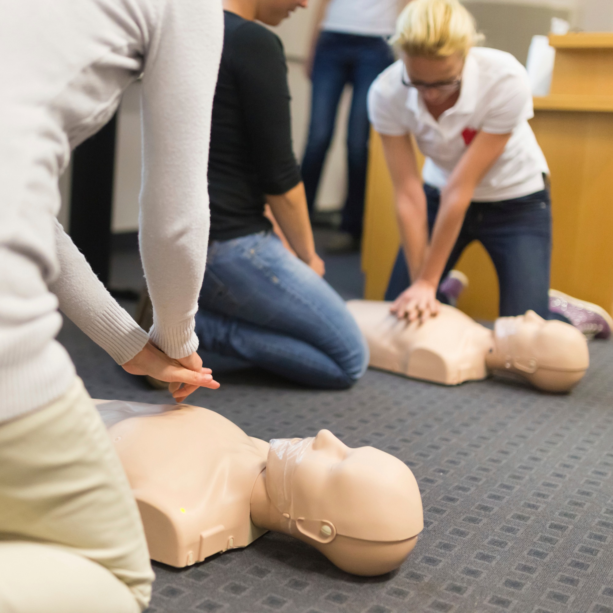 People practising CPR on mannequins during a {{search_term}} by {{company_name}} in {{place}}.