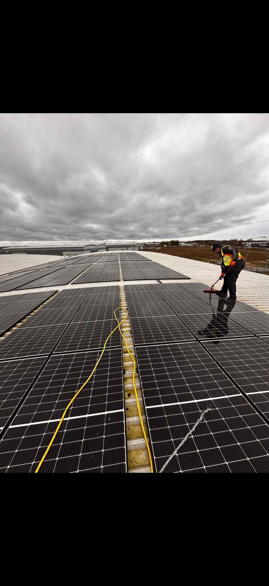 Electrician cleaning solar panels on a rooftop under cloudy skies, showcasing {{company_name}}'s expertise in {{search_term}}.