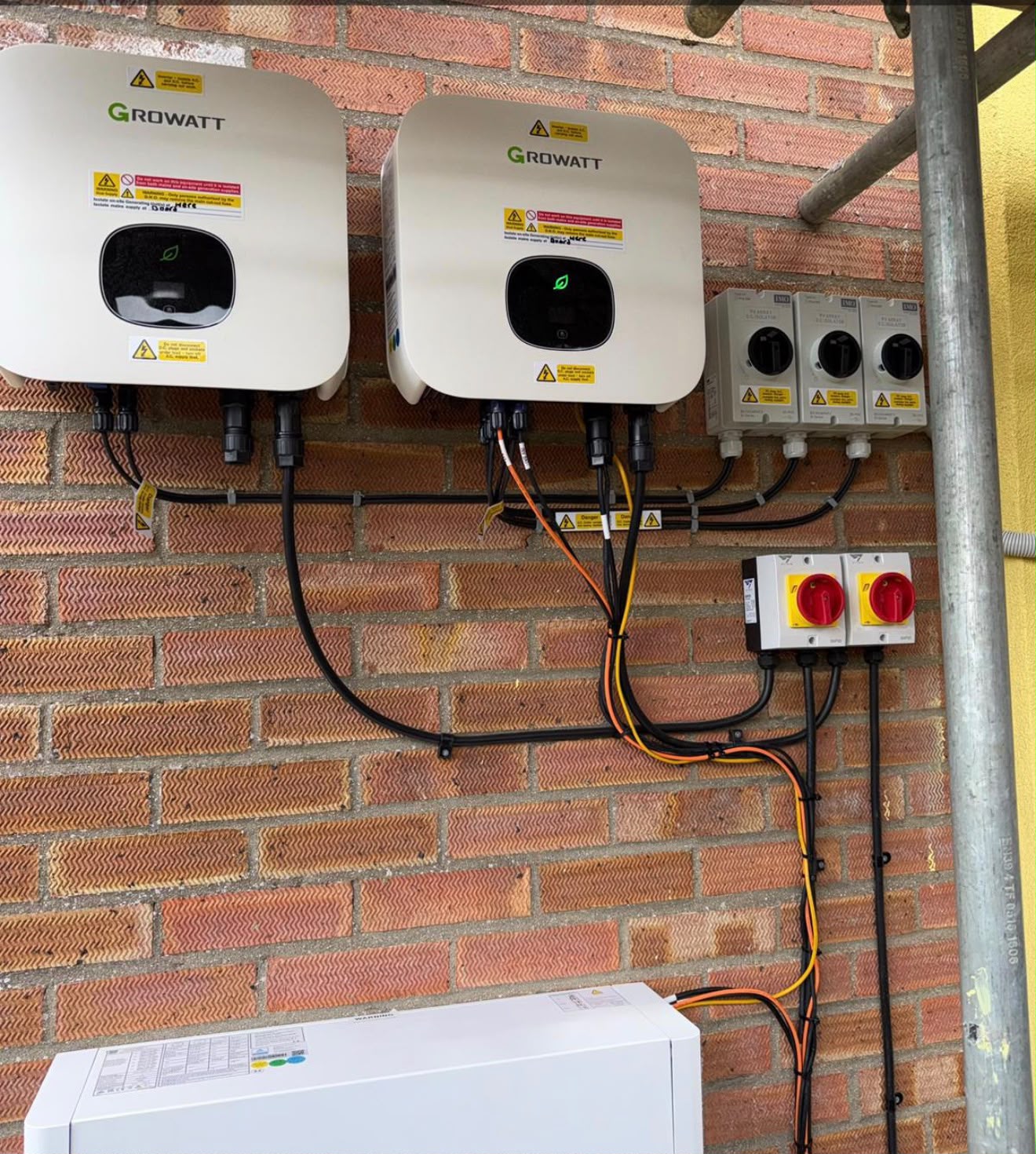 Solar inverters and electrical components mounted on a brick wall, installed by {{company_name}} in {{place}}.