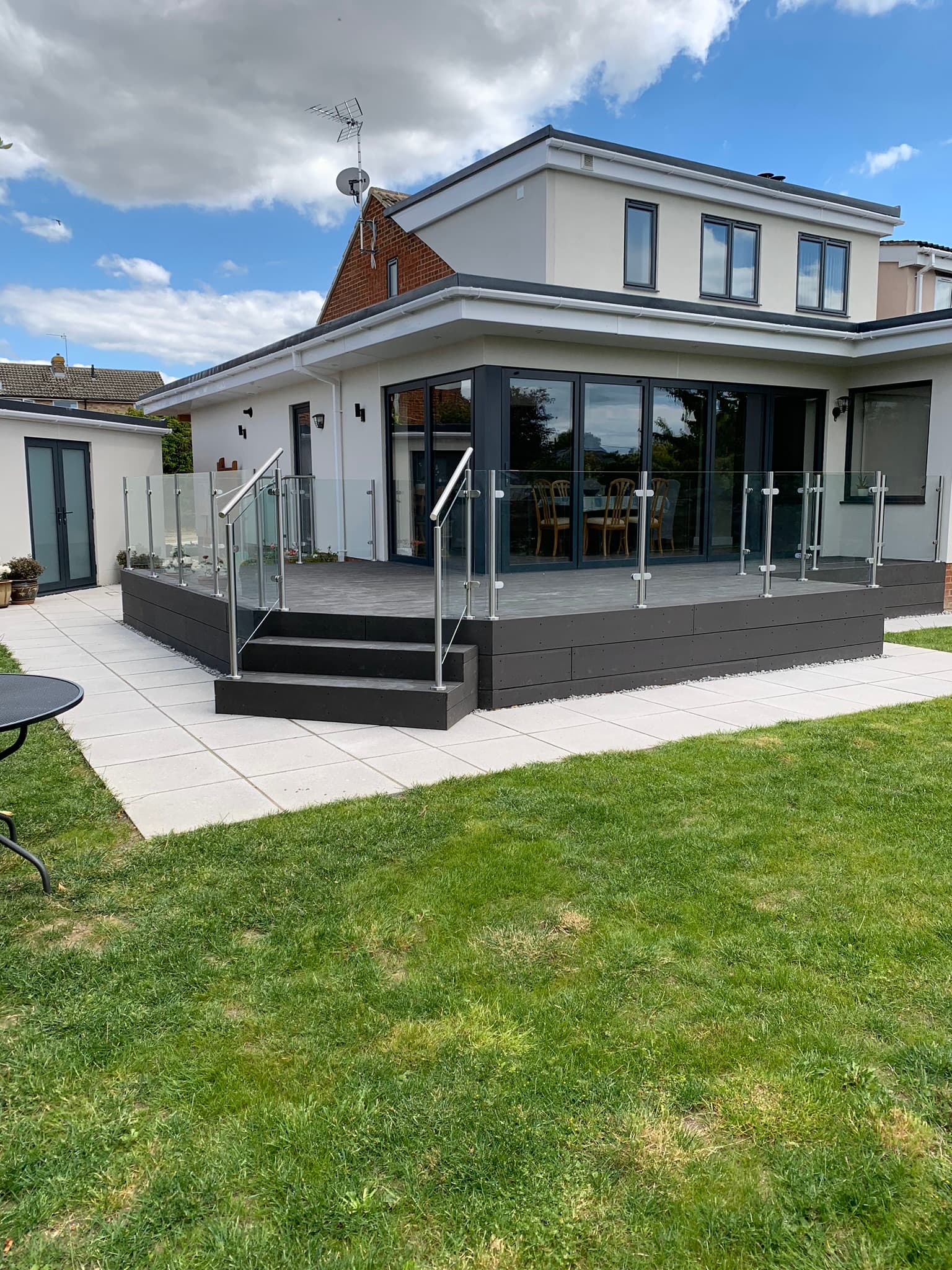 Modern home with glass balustrades on a raised patio, showcasing FOL Design Ltd's bespoke Glass Balustrades &amp; Handrails in Duxford.