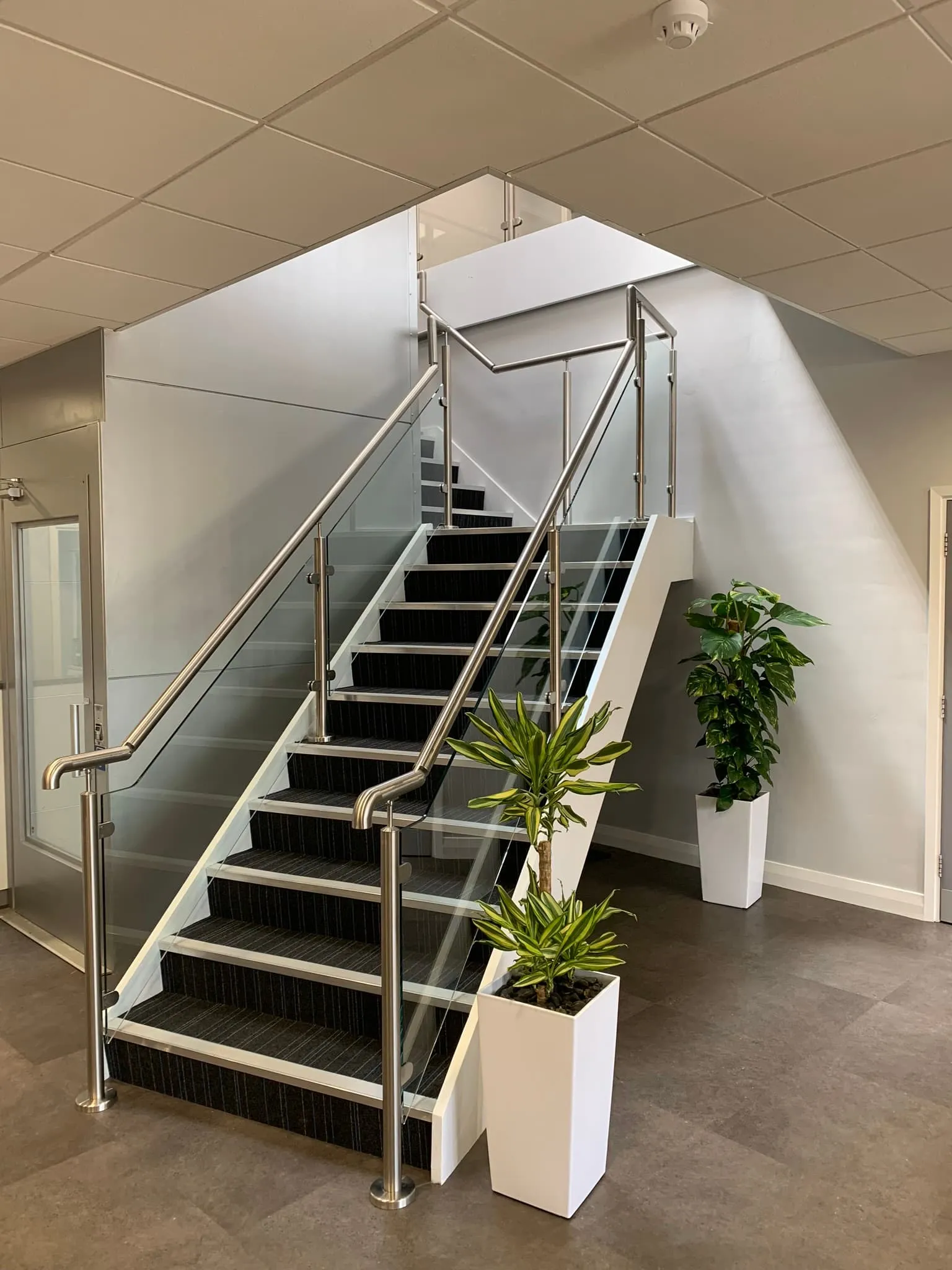 Modern staircase with glass balustrades and stainless steel handrails, showcasing FOL Design Ltd's bespoke Glass Balustrades &amp; Handrails in Chelsea.
