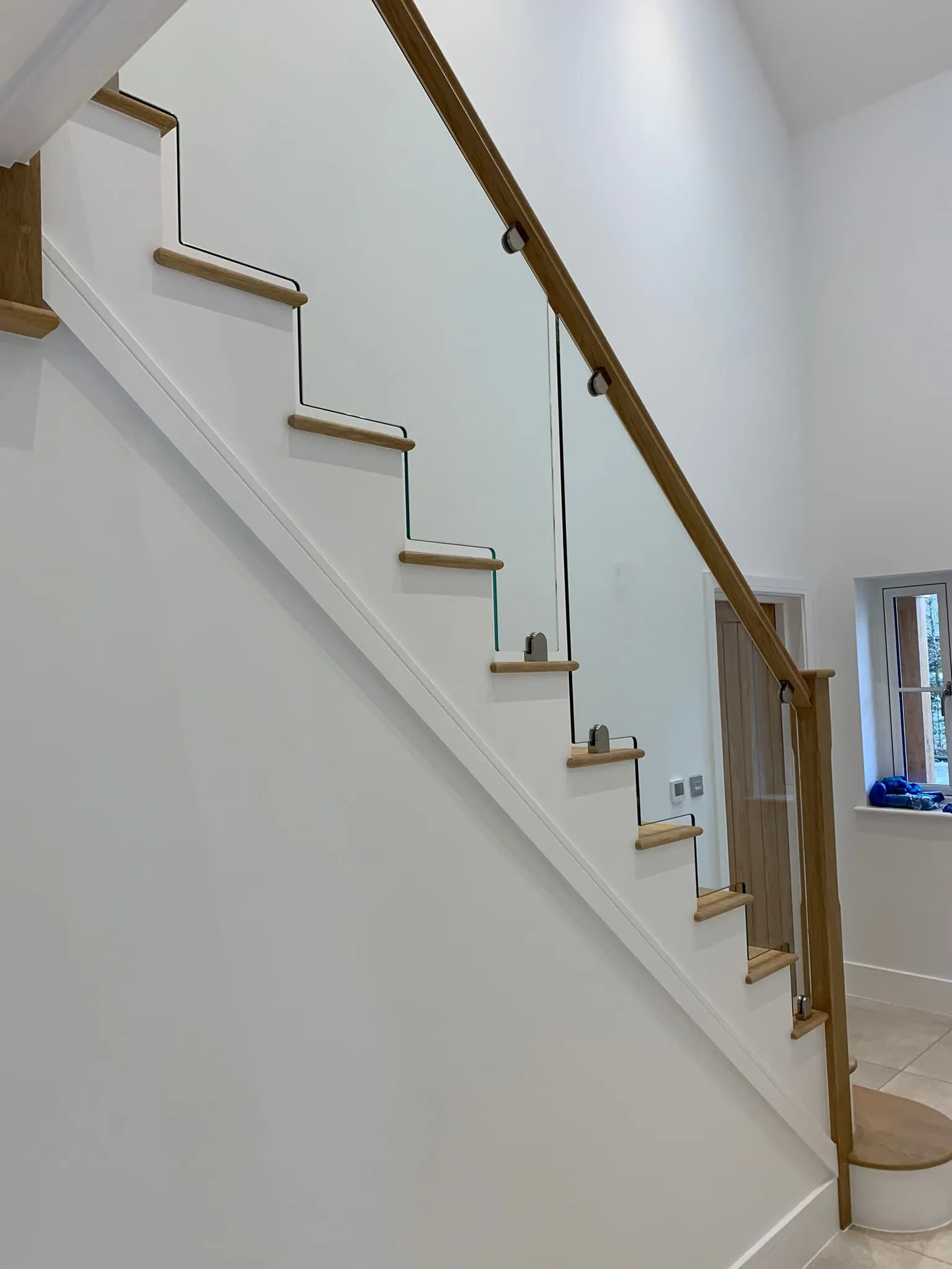 Glass balustrade with wooden handrail on a staircase, showcasing FOL Design Ltd's bespoke Glass Balustrades &amp; Handrails solutions in Duxford.
