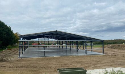 Steel framework of a large building under construction on a cleared site, illustrating services by {{company_name}} for {{search_term}} in {{place}}.