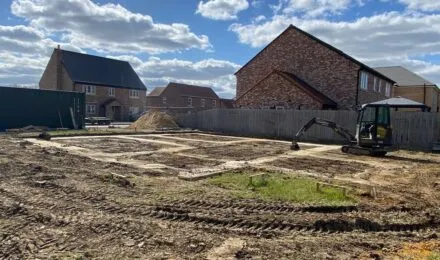 A digger operates on a residential construction site, showcasing MJ Digger &amp; Driver Hire Services's Digger &amp; Driver Hire services in Thetford.