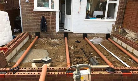 Residential construction site with exposed groundwork and drainage pipes, showcasing {{company_name}}'s {{search_term}} services in {{place}}.