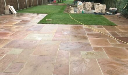 Freshly laid patio with stone slabs and adjacent lawn area, showcasing groundwork services by {{company_name}} in {{place}}.