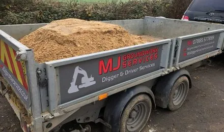 Trailer loaded with sand featuring MJ Digger &amp; Driver Hire Services branding, highlighting Digger &amp; Driver Hire in Brandon.