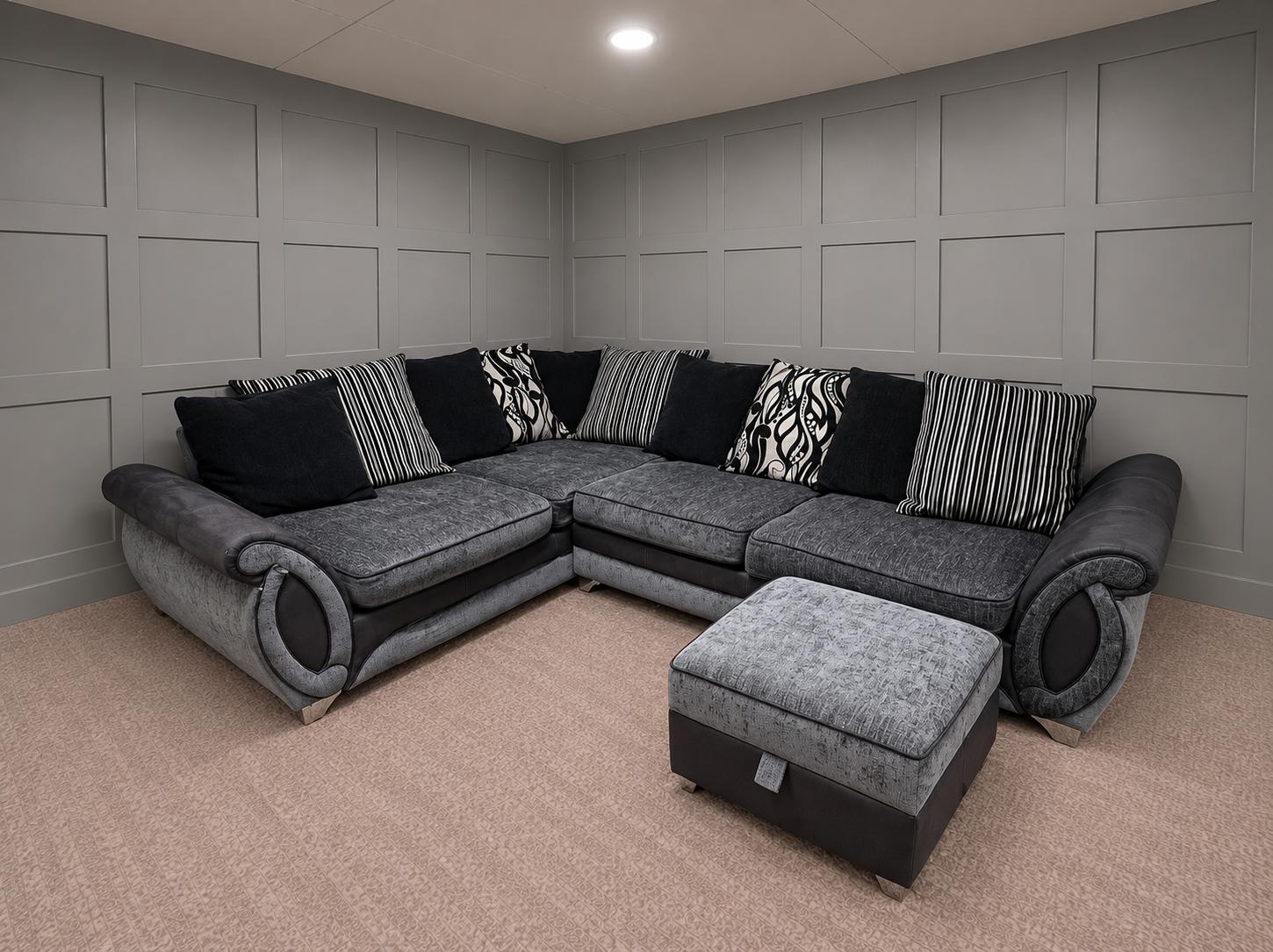 Grey and black corner sofa with patterned cushions and footstool in a showroom, for Restored Living in Clacton-on-Sea
